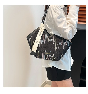 Detailed view of black tote bag featuring V-shaped opening and colorful wave embroidery