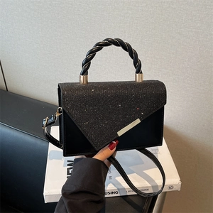 Elegant black shoulder bag with gold hardware and glitter texture on the flap cover