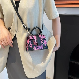Pink snake-print mini handbag with black trim and gold rivets shown on a model