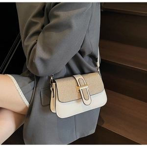 Detail of elegant beige square crossbody bag with gold glitter flap worn over a grey blazer