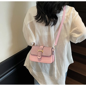 Pink crossbody bag with glitter flap and gold H buckle shown on model in stairwell