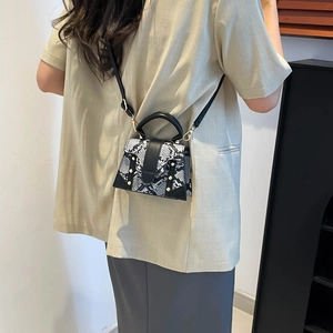 Stylish python print crossbody bag with black handle and gold studs worn by a model