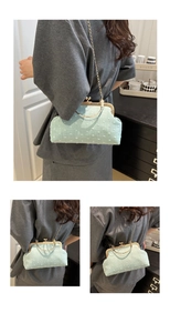 Detail of mint green frame bag with gold ring handle and chain strap on a model