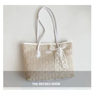 Detailed view of beige woven tote bag with lace bow and white leather handles