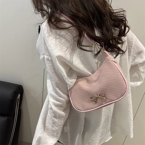 Pink woven underarm shoulder bag with golden metal bow detail and slim strap