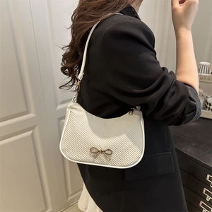 Chic off-white woven underarm bag with gold bow buckle in a stylish shoulder carry view