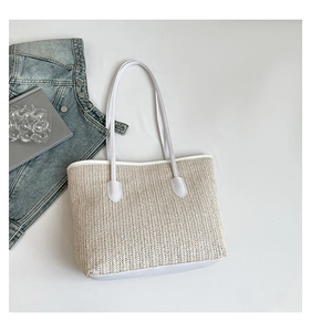 Flat-lay view of a large woven straw tote bag with white leather trim and straps