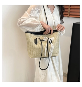 Detail of straw woven bucket bag featuring delicate lace bow and black handle trim