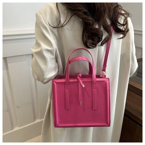 Detail view of pink square handbag with glossy finish and golden metal pendant detail