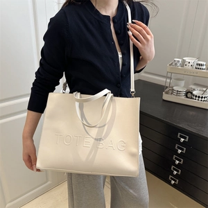 Minimalist creamy white tote bag with embossed lettering and adjustable shoulder strap