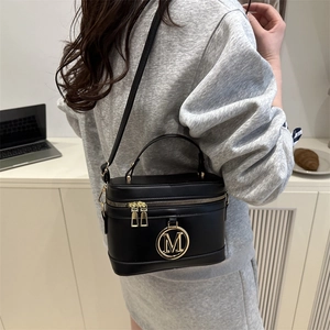 Classic black cylindrical leather crossbody bag with golden M logo and handle