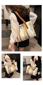 Detailed view of vertical striped canvas tote bag with brown leather handles and side straps