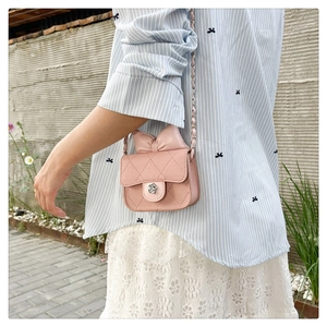 Detail showing the pink quilted mini bag with leather bow and flower buckle on a model