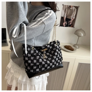 Detail of checkered denim bag with golden deer pendant and elegant chain strap