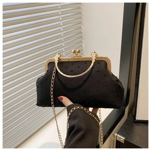 Detailed view of black textured shell evening bag with vintage gold metal frame and handle