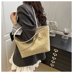Detail of beige straw tote bag with V-pattern weaving and slender leather shoulder strap