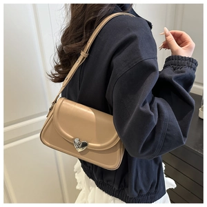 Detail view of beige shoulder bag featuring a silver heart-shaped metal clasp and strap