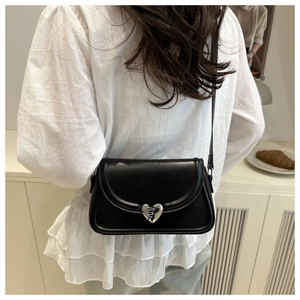 Detailed view of a black faux leather crossbody bag featuring a silver heart-shaped clasp