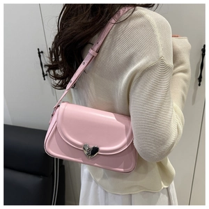 Detail view of pink leather shoulder bag with a silver heart-shaped metal buckle clasp
