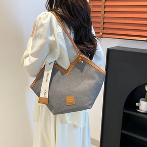 Large gray canvas tote bag with brown leather straps and fashion label on a model