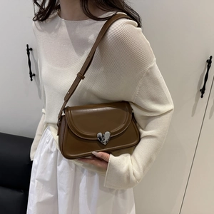 Brown leather half-moon shoulder bag with silver heart buckle on a lifestyle model