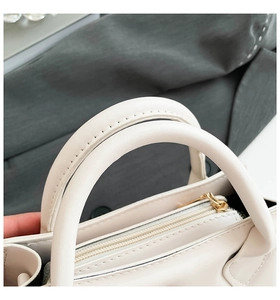 Detailaufnahme der Nähte am Griff und des goldenen Reißverschlusses der weißen Handtasche