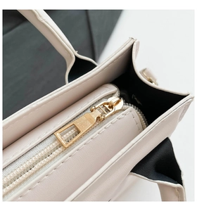 Nahaufnahme von goldenem Reißverschluss und feinen Nähten auf beiger Kunstledertasche