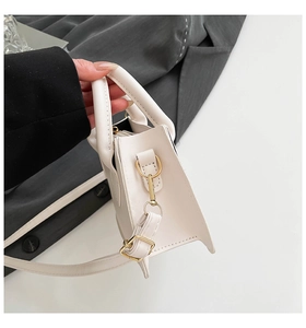 Detailansicht der weißen Handtasche mit Fokus auf goldene Beschläge und Ledertextur