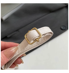 Detail eines verstellbaren beigen Kunstlederriemens mit goldener Metallschnalle und feiner Naht