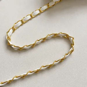 Detail of woven white leather and golden metal chain strap with elegant stitching