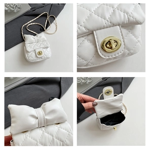 Detail view of white quilted crossbody bag with bow, gold chain strap and turn-lock