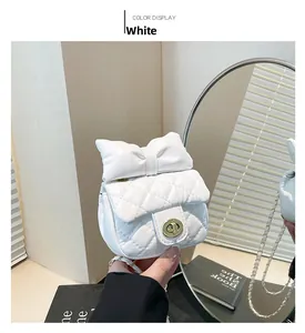 Detailed shot of white quilted mini bag with a large bow and gold chain strap
