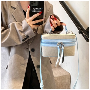 Detail of a mini beige woven bag with light blue leather trim and dual zippers