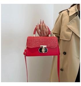 Détail d'un sac carré rouge avec rabat scintillant et boucle métallique en forme de T