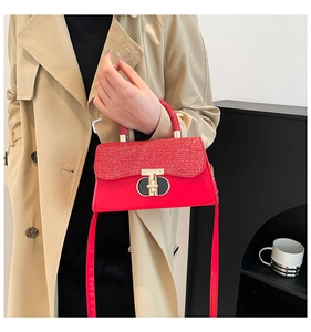 Détail du sac à main rouge pailleté avec fermoir doré en T et bandoulière réglable