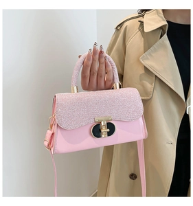 Détail d'un sac à main rose à strass avec fermoir doré et bandoulière en cuir