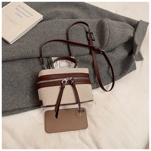 Detail of a vintage box bag in woven canvas and brown leather showing size comparison with phone