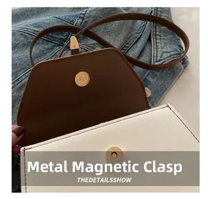 Close-up of magnetic hardware buckle on vintage contrast stitching crossbody bag