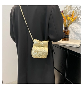 Close-up of champagne gold quilted mini bag with a large bow and gold chain strap