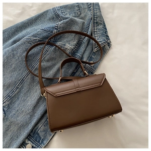 Detail of dark brown leather handbag with metal base studs on denim background