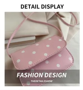Close-up of pink polka dot leather handbag with shoulder strap and flap closure details