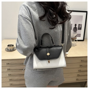 Detail view of contrast color handbag with golden metal buckle and top handle feature