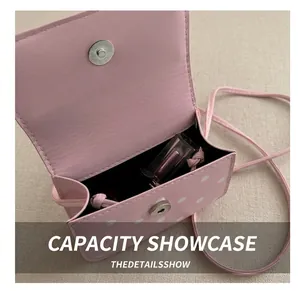 Pink polka dot mini shoulder bag showing interior capacity with a lipstick