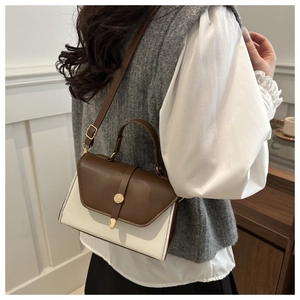 Detail of a color-block leather crossbody bag with golden hardware on a female model
