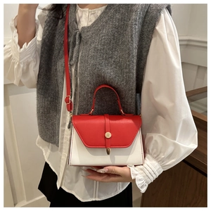 Detail of red and white contrast leather bag worn with casual outfit showing size scale