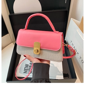 Detail einer Umhängetasche aus Leder in Pink und Webstoff mit goldenem Verschluss