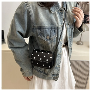 Mini sac à pois porté avec une veste en jean et une robe blanche pour un look chic