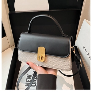 Detailansicht der Kontrasttasche mit schwarzer Lederklappe und goldenem Drehverschluss