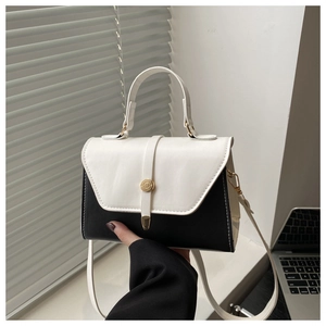 Detail of minimalist black and white crossbody bag with golden round clasp and fine stitching