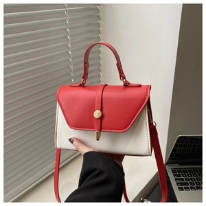 Detail of red and white minimalist handbag featuring a gold round buckle and leather handle